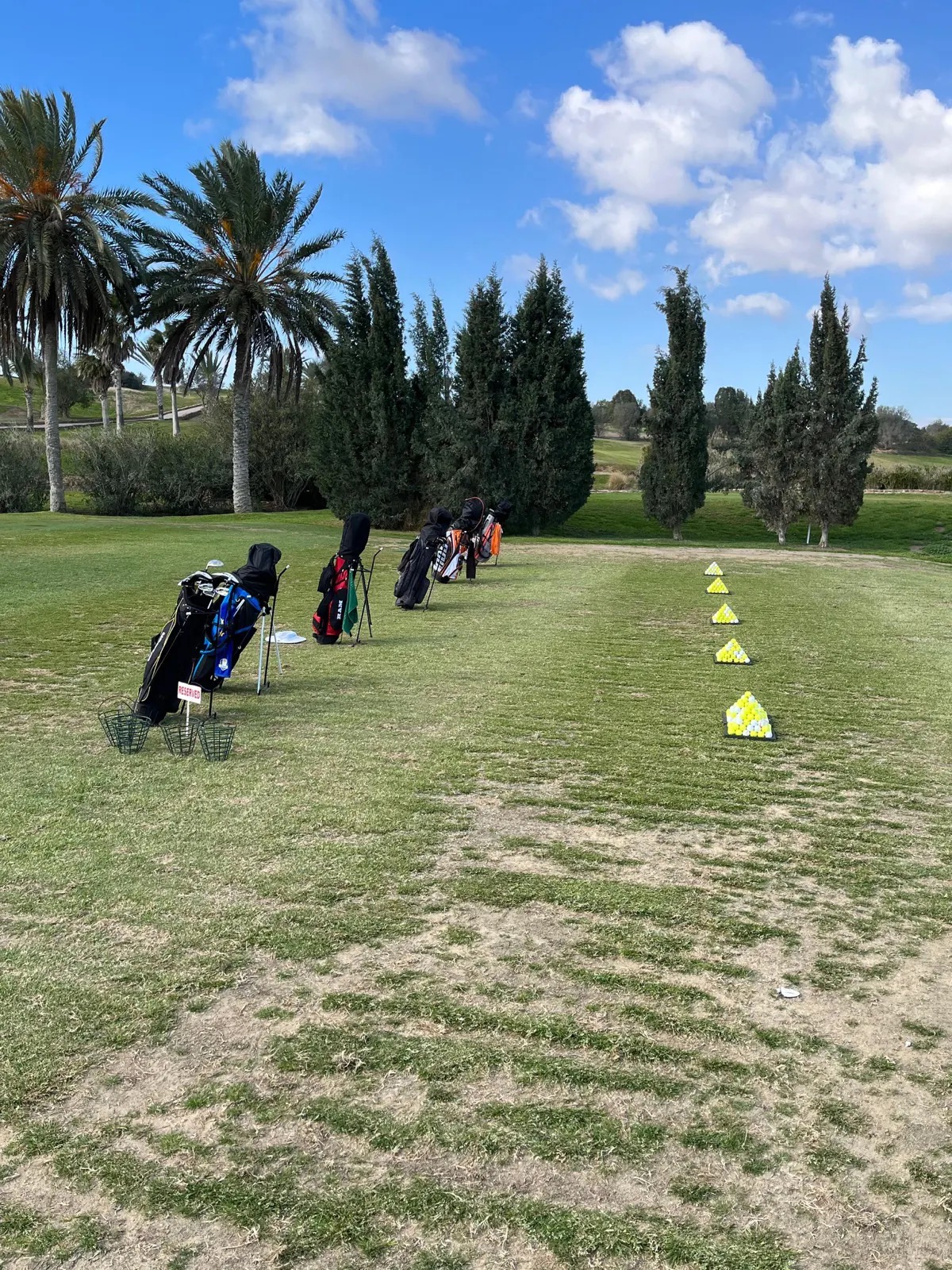 Stage golf hébergement Tunisie — sacs de golf alignés sur le practice